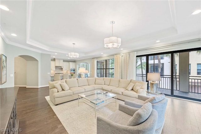 2745 Tiburon Blvd E Unit 102, Naples, FL 34109 - living area featuring a tray ceiling, arched walkways, dark wood-style floors, crown molding, and a chandelier