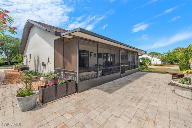 6721 Southwell Dr, Fort Myers, FL 33966 - back of property featuring a sunroom, a patio, and stucco siding
