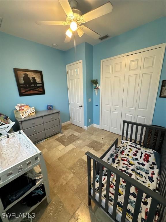 bedroom featuring light stone finish floors, a closet, and a ceiling fan