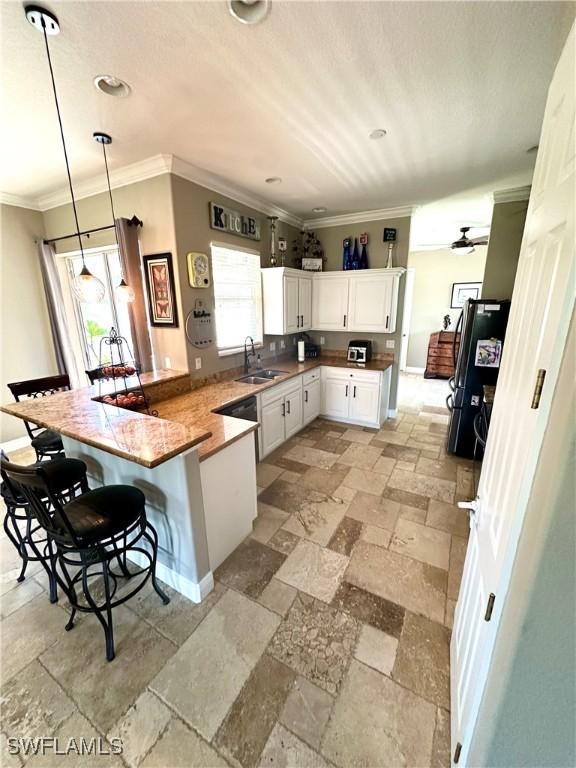 kitchen with a peninsula, stone tile flooring, plenty of natural light, ornamental molding, and recessed lighting