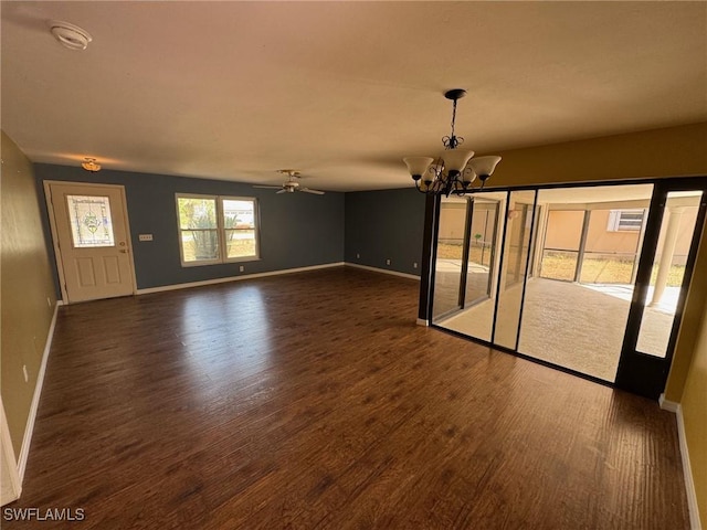 unfurnished dining area with a chandelier, dark wood-style flooring, baseboards, and a ceiling fan