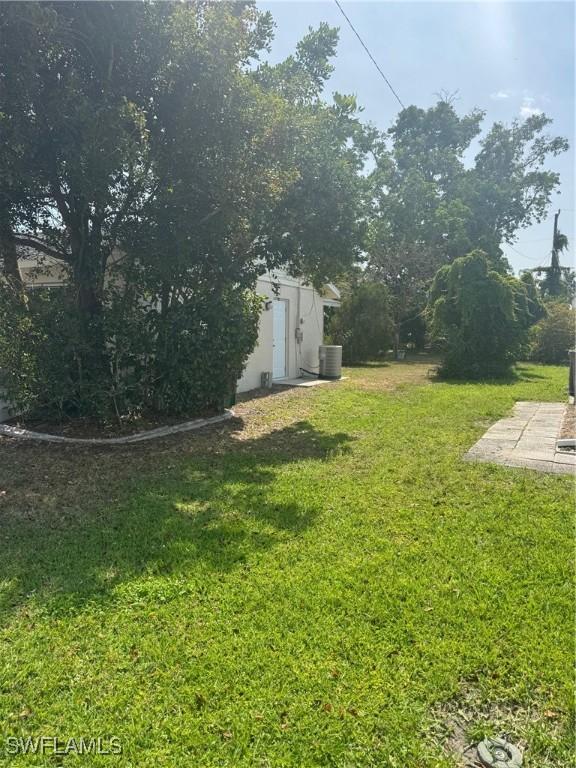 view of grassy yard featuring cooling unit, a storage unit, and a patio