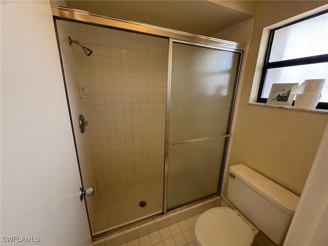 full bath featuring a stall shower, toilet, and tile patterned floors