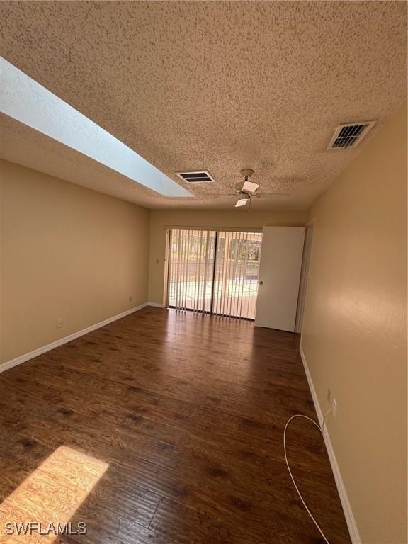 unfurnished room featuring baseboards, wood finished floors, a textured ceiling, and ceiling fan