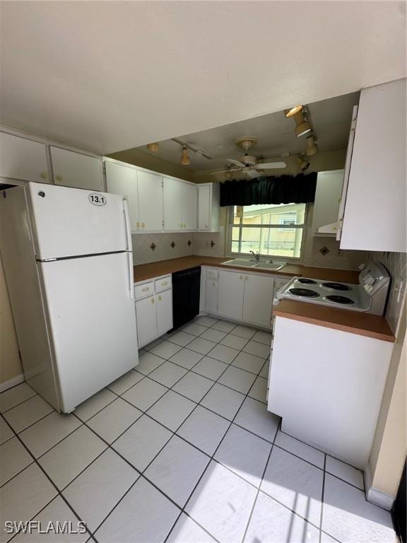kitchen with white appliances, a sink, white cabinets, rail lighting, and light tile patterned floors