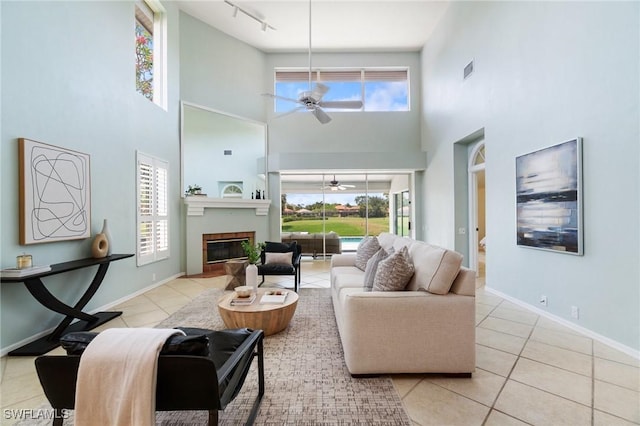 10334 Quail Crown Dr, Naples, FL 34119 - tiled living area featuring ceiling fan, a high ceiling, a glass covered fireplace, track lighting, and baseboards