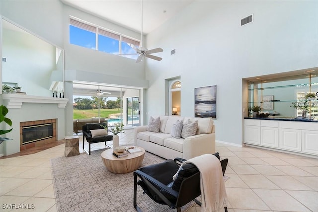 10334 Quail Crown Dr, Naples, FL 34119 - living area with a ceiling fan, light tile patterned floors, a high ceiling, a tiled fireplace, and baseboards