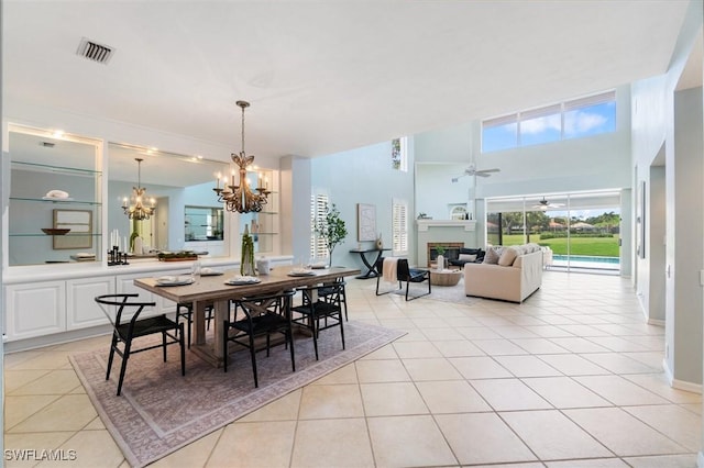 10334 Quail Crown Dr, Naples, FL 34119 - dining space featuring light tile patterned floors, a chandelier, a glass covered fireplace, a towering ceiling, and ceiling fan