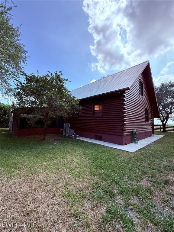 304 Flagler St, Clewiston, FL 33440 - view of home's exterior featuring log exterior, a yard, and metal roof