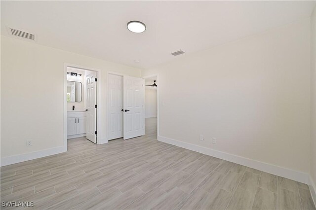 4733/4735 28th St SW, Lehigh Acres, FL 33973 - unfurnished bedroom with baseboards, light wood finished floors, and ensuite bathroom