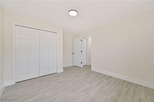4733/4735 28th St SW, Lehigh Acres, FL 33973 - unfurnished bedroom featuring baseboards, light wood-style flooring, and a closet