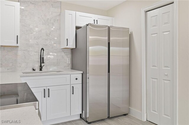 4733/4735 28th St SW, Lehigh Acres, FL 33973 - kitchen with freestanding refrigerator, a sink, white cabinetry, decorative backsplash, and light countertops
