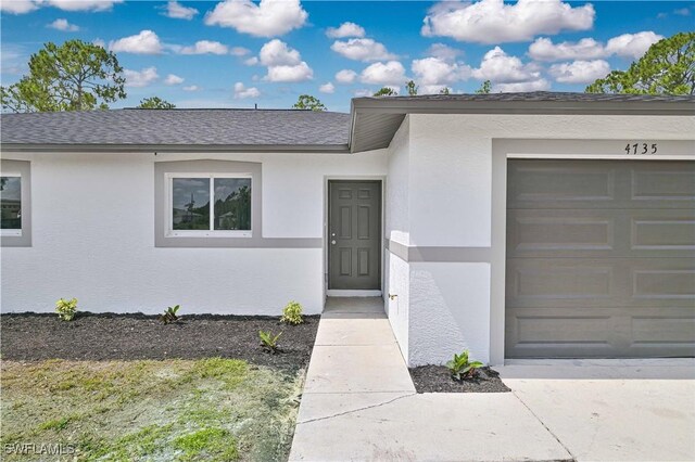 4733/4735 28th St SW, Lehigh Acres, FL 33973 - doorway to property featuring a garage, stucco siding, and roof with shingles