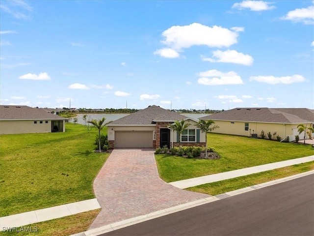 single story home with decorative driveway, a garage, a front yard, and a water view