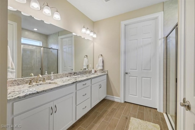 bathroom featuring a stall shower, double vanity, baseboards, and wood tiled floors
