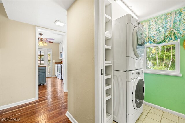 laundry room with stacked washer / drying machine, baseboards, ceiling fan, and wood finished floors