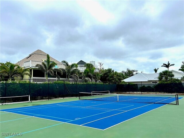 view of tennis court with community basketball court and fence