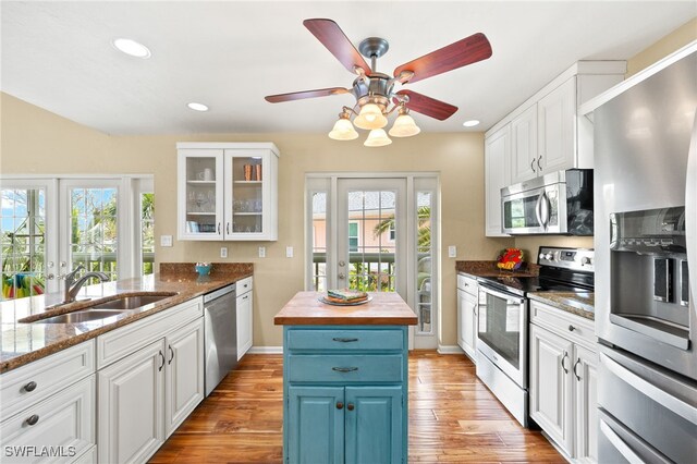 kitchen with appliances with stainless steel finishes, a sink, blue cabinetry, white cabinetry, and recessed lighting