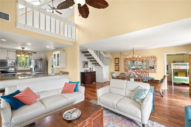 living area featuring stairs, wood finished floors, a chandelier, ceiling fan, and recessed lighting