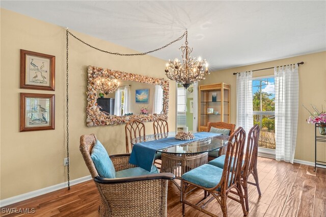 dining space featuring a chandelier, wood finished floors, and baseboards