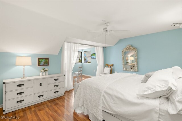 bedroom featuring light wood-style flooring, baseboards, a ceiling fan, and lofted ceiling