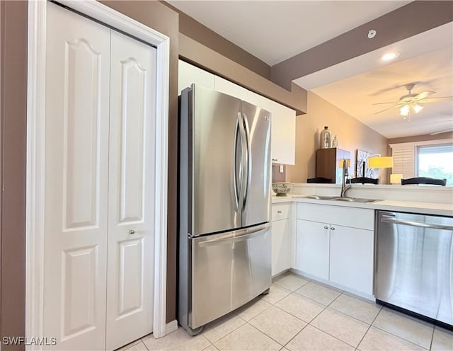 kitchen with stainless steel appliances, a sink, light countertops, and light tile patterned floors