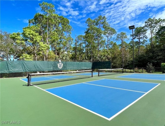 view of tennis court featuring community basketball court and fence