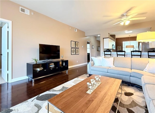 living room featuring wood finished floors, baseboards, and a ceiling fan