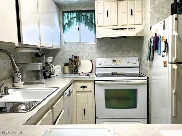 kitchen with white appliances, under cabinet range hood, light countertops, white cabinetry, and a sink