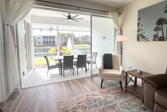 living room featuring a ceiling fan, wood finished floors, and a water view