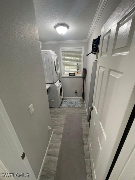5570 Cypresswoods Resort Dr, Fort Myers, FL 33905 - laundry area with stacked washer / dryer, ornamental molding, baseboards, wood finished floors, and a textured ceiling