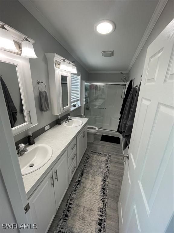 5570 Cypresswoods Resort Dr, Fort Myers, FL 33905 - full bath with a shower stall, toilet, crown molding, double vanity, and wood finished floors