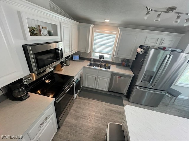 5570 Cypresswoods Resort Dr, Fort Myers, FL 33905 - kitchen with appliances with stainless steel finishes, crown molding, white cabinets, a sink, and light countertops