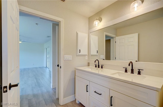 bathroom with wood finished floors, double vanity, and baseboards