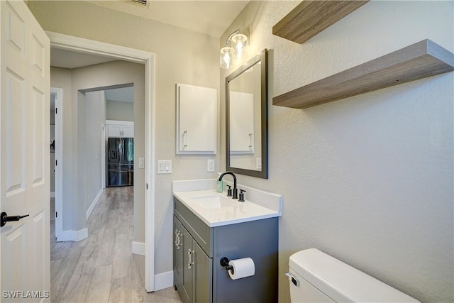 bathroom featuring wood finished floors, toilet, baseboards, and vanity