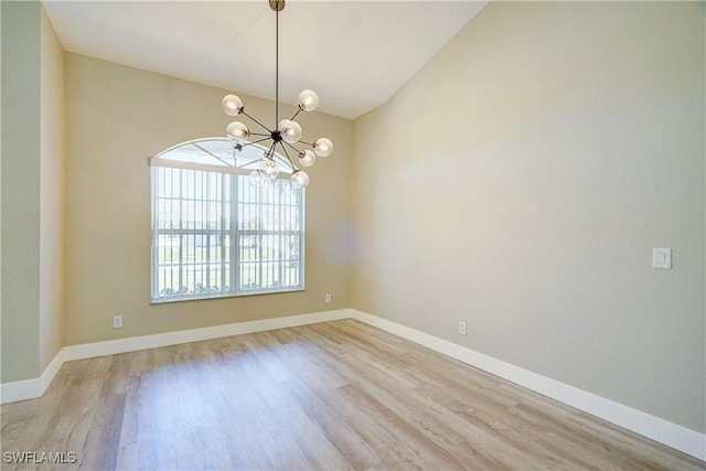 spare room with a chandelier, light wood-style floors, baseboards, and lofted ceiling