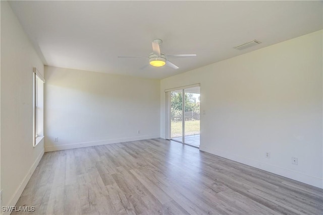 spare room featuring light wood-type flooring, ceiling fan, and baseboards