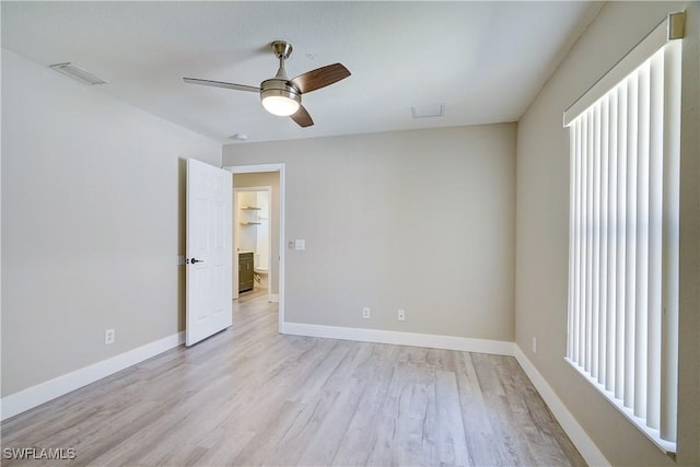 spare room featuring a ceiling fan, light wood finished floors, and baseboards