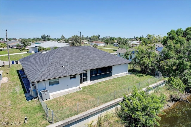 back of house with roof with shingles, a residential view, stucco siding, central air condition unit, and a sunroom