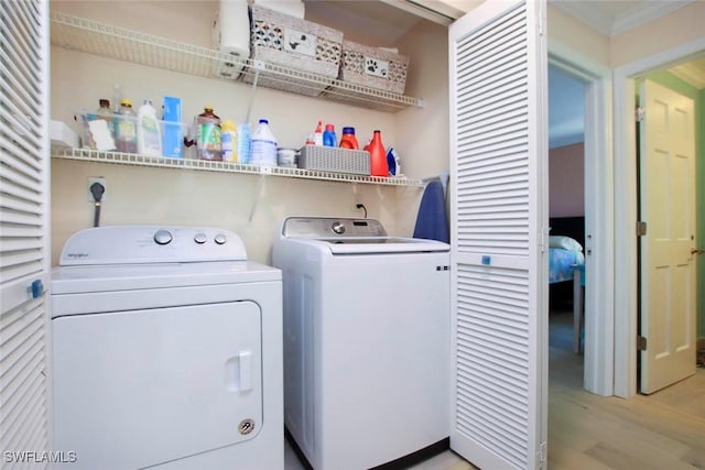 laundry area with washing machine and clothes dryer, light wood-style floors, and crown molding