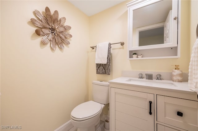 half bath with toilet, vanity, and baseboards