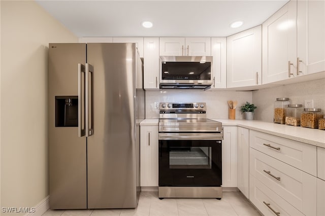kitchen with appliances with stainless steel finishes, light countertops, white cabinetry, light tile patterned floors, and recessed lighting
