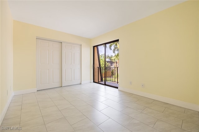 unfurnished bedroom featuring access to outside, baseboards, a closet, and light tile patterned floors