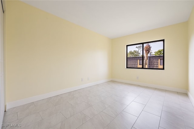 spare room featuring baseboards and light tile patterned floors