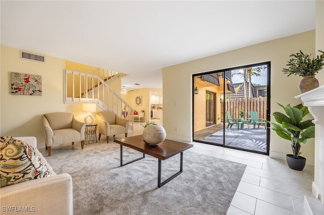 living room with stairs, tile patterned floors, and baseboards