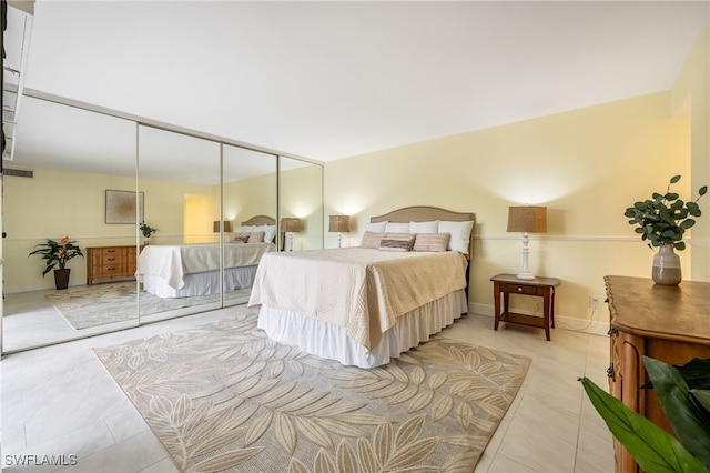 bedroom featuring tile patterned floors, a closet, and baseboards