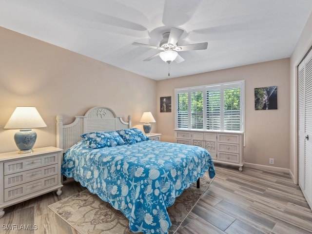 bedroom featuring wood finished floors, baseboards, a ceiling fan, and a closet