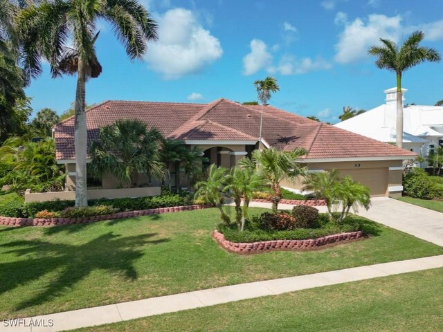 mediterranean / spanish-style house featuring an attached garage, concrete driveway, a front lawn, a tile roof, and stucco siding