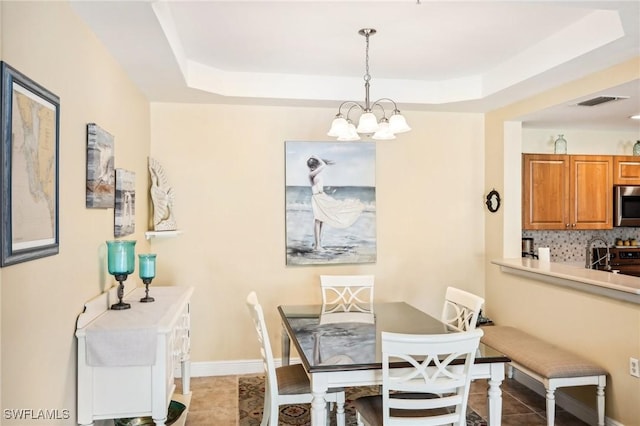 1520 SW 50th St Unit 202, Cape Coral, FL 33914 - dining space with a tray ceiling, a chandelier, light tile patterned flooring, and baseboards