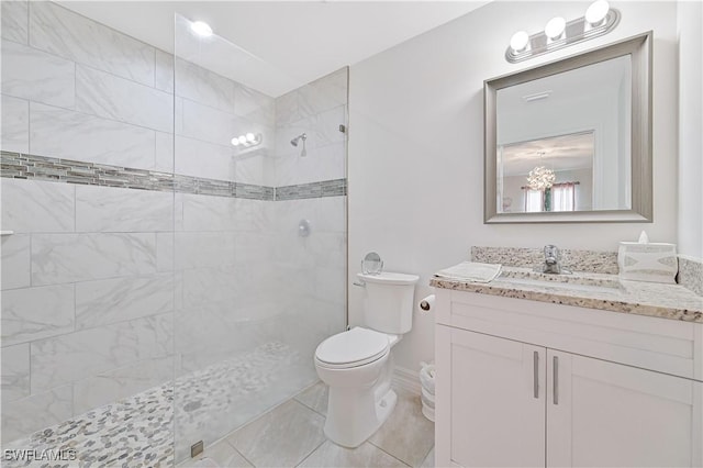 full bathroom with toilet, tiled shower, vanity, and tile patterned floors
